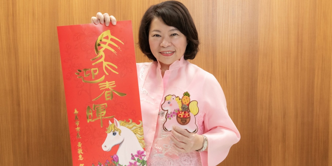 ▲市長黃敏惠開心展示分別由插畫家、書法家獨特設計的「粉紅超馬」小紅包以及「馬迎春暉」春聯。(圖/嘉義市政府提供)